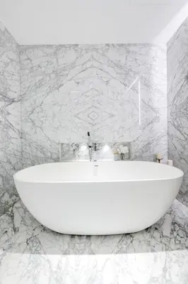a white bath tub in a bathroom with marble walls at Grand Dubai Marina 4BR Triplex with Pool Gym Sauna in Dubai