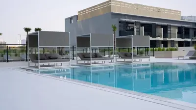 a swimming pool with chairs and a building at Sleek 1br Apt Jvc Quiet Space With Pool & Par in Dubai
