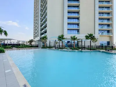 a large swimming pool in front of a building at Unbeatable Rate Modern 2BR with Partial Canal Views by Deluxe Holiday Homes in Dubai