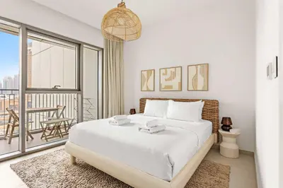 a white bedroom with a bed and a balcony at Silkhaus Deluxe 2BR in Downtown Views II in Dubai
