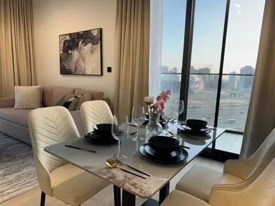 a dining room with a table and chairs with a view at ASHRI HH Spacious Apartment in JVC, Binghatti Luna in Dubai