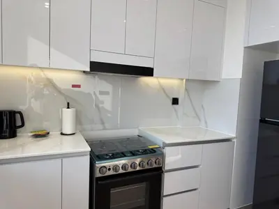 a white kitchen with a stove and white cabinets at ASHRI HH Spacious Apartment in JVC, Binghatti Luna in Dubai