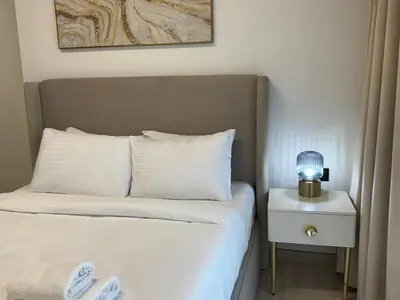 a bedroom with a bed with a lamp on a nightstand at ASHRI HH Spacious Apartment in JVC, Binghatti Luna in Dubai