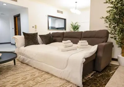 a living room with a large couch with towels on it at Palm & Sea View 2BR JBR Beach Oasis 1 in Dubai