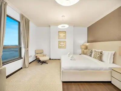 a bedroom with a bed and a chair and a window at Palm & Sea View 2BR JBR Beach Oasis 1 in Dubai