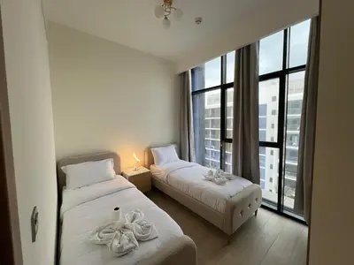 two beds in a room with a large window at Spacious Comfortable Apartment for your Family or you Group in Dubai