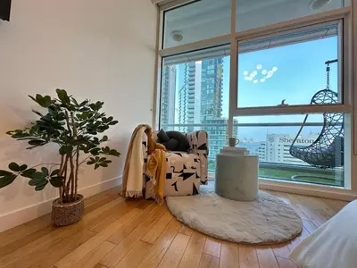 a living room with a chair and a large window at Opulent Flat with Beach, Pool & Canal View in JBR in Dubai