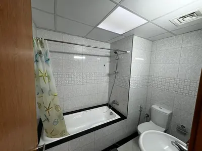 a bathroom with a tub and a toilet and a sink at Specious Fully furnished studio in May residence in Dubai
