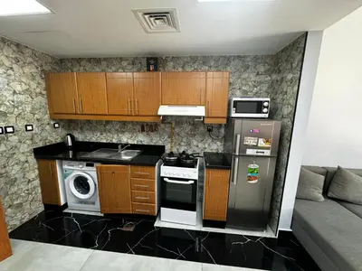 a kitchen with a stove and a microwave at Specious Fully furnished studio in May residence in Dubai