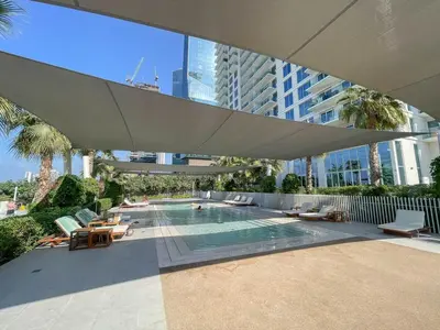a swimming pool with chairs and a large umbrella at Beautiful 2 Bedroom Sea Views at La Vie JBR in Dubai