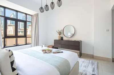a white bedroom with a large bed and a mirror at Frank Porter - Tajer Tower E in Dubai