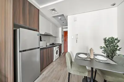 a kitchen with a table and a refrigerator at Stunning Lake View Apartment in JLT in Dubai