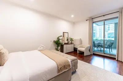 a white bedroom with a bed and a balcony at Chic 1-Bedroom Getaway with Downtown Living Charm in Dubai