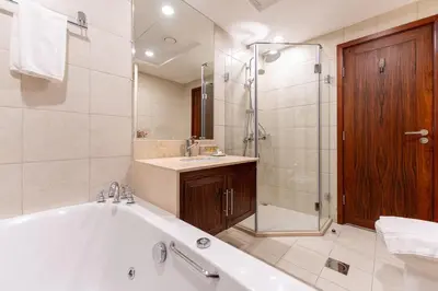 a bathroom with a tub and a shower and a sink at Chic 1-Bedroom Getaway with Downtown Living Charm in Dubai