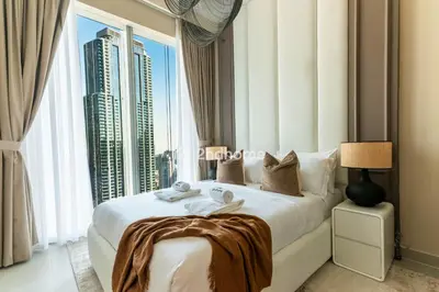 a bedroom with a large bed with a large window at Unit Overlooking Burj Khalifa and Fountain View in Dubai