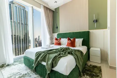 a bedroom with a large green bed with red pillows at Unit Overlooking Burj Khalifa and Fountain View in Dubai