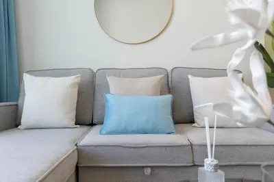 a gray couch with pillows and a blue pillow at Sky-High Serenity - Stylish 1BHK - 20th Floor in Dubai