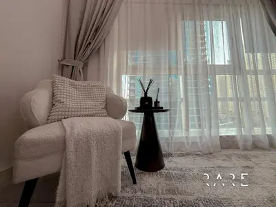 a living room with a chair and a window at Rare Holiday Homes - Marina Quays West Tower - Near the Beach - R1003 - Dubai Marina in Dubai