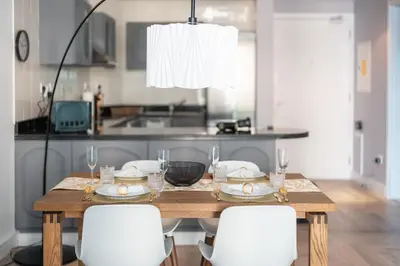 a dining room table with white chairs and a kitchen at Damac Waves Tower Dubai Marina - By Home Of Choice in Dubai