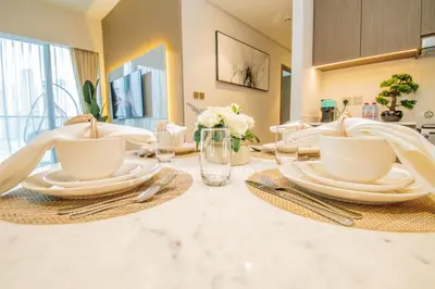 a dining room table with white plates and utensils at GRANDE SIGNATURE- 2BR Apartment with full Burj Khalifa views in Dubai