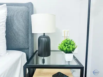 a black lamp on a glass table next to a bed at Modern Studio in Business Bay Capital Bay Tower in Dubai