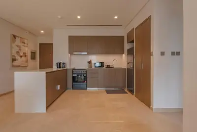a large kitchen with wooden cabinets and a counter at Downtown Luxury - Elegant 1-Bedroom Apartment - 5 Minutes Walk to Dubai Mall in Dubai