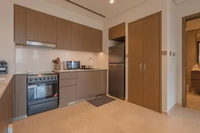 a kitchen with wooden cabinets and a stove at Downtown Luxury - Elegant 1-Bedroom Apartment - 5 Minutes Walk to Dubai Mall in Dubai