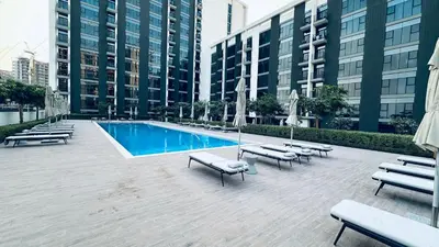 a pool with chaises and benches next to tall buildings at One bedroom apartment brand new Dubai Hills ultra luxury furniture in Dubai