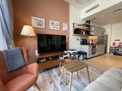 a living room with a couch and a tv and a table at Luxe Escape at Dubai Hills in Dubai