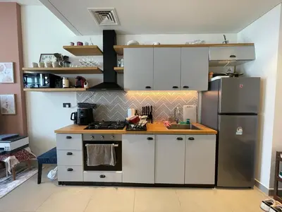 a kitchen with white cabinets and a stainless steel refrigerator at Luxe Escape at Dubai Hills in Dubai