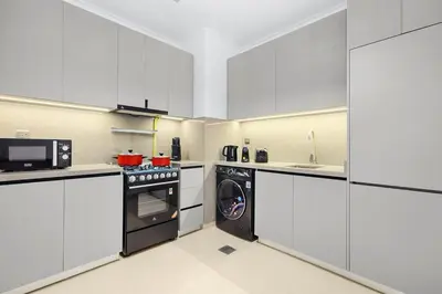 a kitchen with white cabinets and a washer at Luxury 1BR City View with Balcony Parking & WiFi Near Dining & Downtown in Dubai