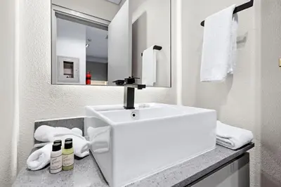 a white bathroom with a sink and a mirror at Luxury 1BR City View with Balcony Parking & WiFi Near Dining & Downtown in Dubai