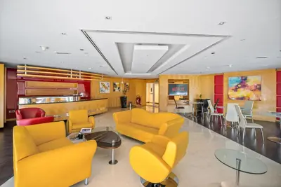 a waiting room with yellow chairs and a table at Modern Studio Apartment in Lake View in Dubai