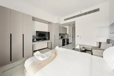 a white bedroom with a large bed and a living room at Bright Studio in MAG Eye in Dubai
