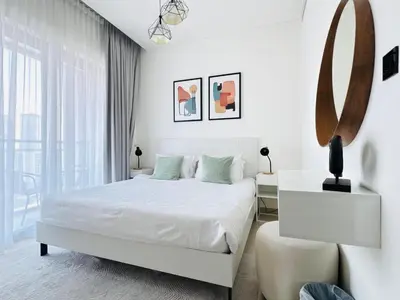 a white bedroom with a white bed and a mirror at Creek Views 1 BR, Mins to Downtown in Sobha Creek Vistas in Dubai