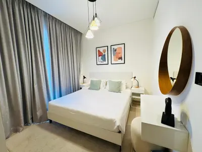 a bedroom with a white bed and a mirror at Creek Views 1 BR, Mins to Downtown in Sobha Creek Vistas in Dubai