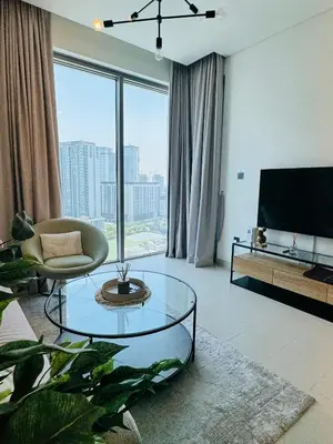 a living room with a glass table and a large window at Creek Views 1 BR, Mins to Downtown in Sobha Creek Vistas in Dubai