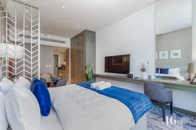 a bedroom with a large white bed with blue pillows at Spacious Studio in Damac Maison Prive Canal Views in Dubai