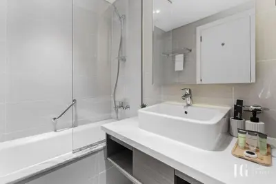 a white bathroom with a sink and a shower at Spacious Studio in Damac Maison Prive Canal Views in Dubai