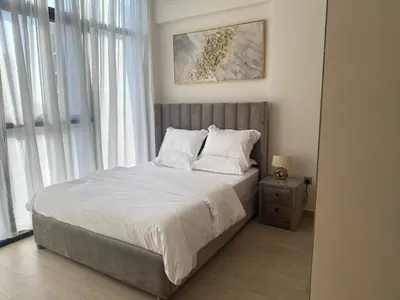 a bedroom with a bed with white sheets and pillows at Cozy 01 BHK with Balcony in Dubai