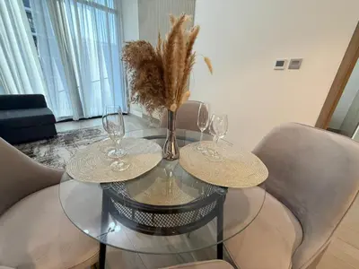 a glass table with three wine glasses on it at Cozy 01 BHK with Balcony in Dubai