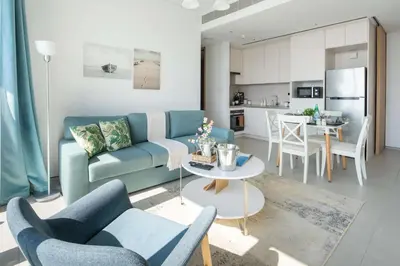 a living room with a blue couch and a kitchen at Frank Porter - Address JBR in Dubai