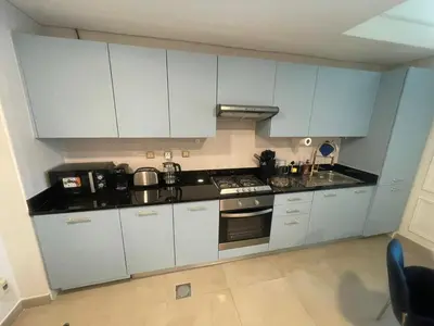 a kitchen with white cabinets and a stove top oven at Elegant 1BR at Sparkle T1 With Marina View Near Beach in Dubai