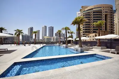 a large swimming pool with palm trees and umbrellas at Elegant 1BR at Sparkle T1 With Marina View Near Beach in Dubai