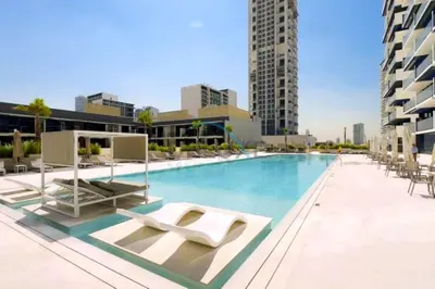 a swimming pool with lounge chairs on a building at Delightful 1BR in Binghatti Corner, Jumeirah Village Circle by Deluxe Holiday Homes in Dubai