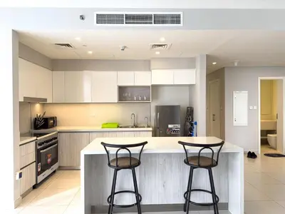 a kitchen with white cabinets and two bar stools at Elegant 3 Bed in Park Point, Dubai Hills Estate in Dubai