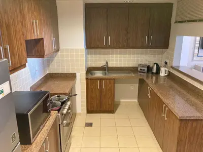 a small kitchen with wooden cabinets and a sink at Executive Tower 1bhk Business Bay in Dubai