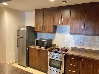 a kitchen with wooden cabinets and a stainless steel refrigerator at Executive Tower 1bhk Business Bay in Dubai