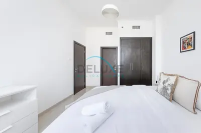 a white bedroom with a large white bed and some doors at Spectacular 1BR in Botanica Tower 1 Dubai Marina by Deluxe Holidy Homes in Dubai