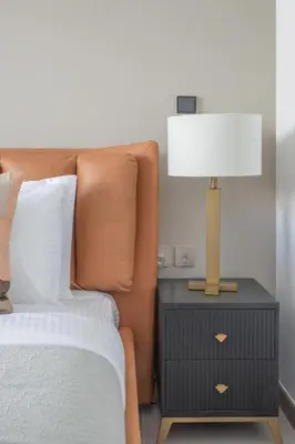 a lamp on a night stand next to a bed at Frank Porter - Urban Oasis in Dubai
